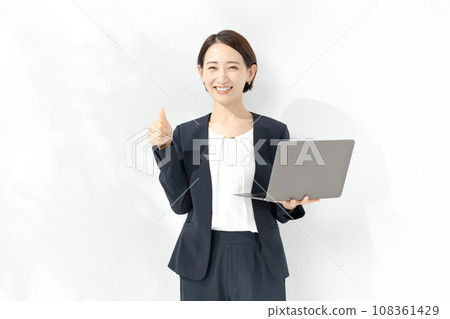 拿著膝上型計算機和做一個好標誌的微笑的女商人 108361429