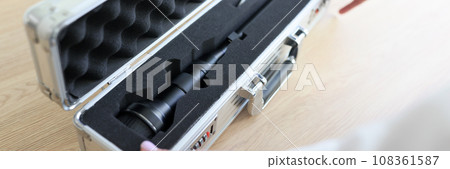 Woman opens silver case with modern Laowa lens for camera 108361587