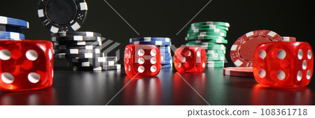 Red dice with white dots scattered on table near poker chips 108361718