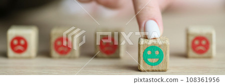 Finger of woman moves out wooden cube with positive emoji Finger of woman moves out wooden cube with positive emoji 108361956