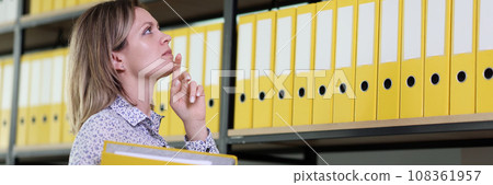 Woman tries to remember position of folder with papers Woman tries to remember position of folder with papers 108361957