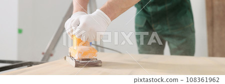 Skilled carpenter polishes wooden surface of office table 108361962