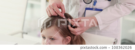 Therapist looks for insects in hair of little patient 108362026