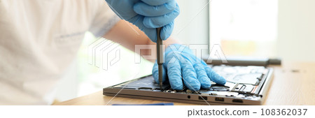 Male master in rubber gloves unscrews printed circuit board 108362037