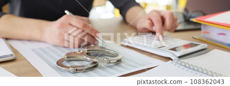 Handcuffs on investigation paper while woman making counts 108362043