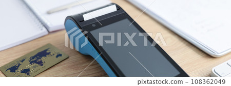 Modern terminal and bank credit cards lie on wooden table Modern terminal and bank credit cards lie on wooden table 108362049