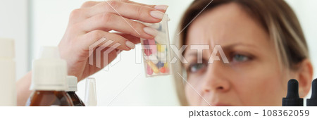Woman with headache reads instruction on bottle with pills 108362059