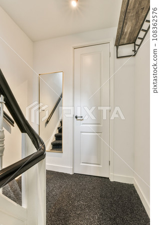 a white staircase with black carpeting and an open door leading to the second floor in a mirror is on the wall a white staircase with black carpeting and an open door leading to the second floor in a mirror is on the wall 108362576