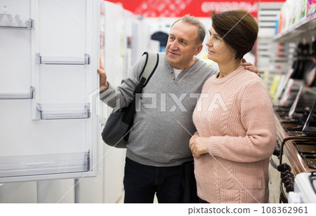Middle aged wife and husband picking new refrigerator in store Middle aged wife and husband picking new refrigerator in store 108362961