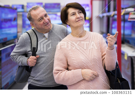 Senior couple picking new TV in tech store 108363131