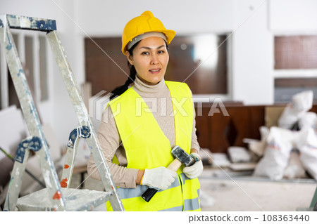 Portrait of positive woman builder standing in apartment 108363440