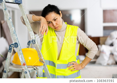 Portrait of tired woman builder standing in apartment 108363591