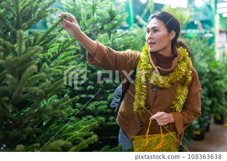 Woman customer buying fir tree at Christmas market 108363638