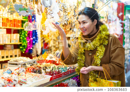 Asian female choosing decorations at Christmas fair Asian female choosing decorations at Christmas fair 108363683
