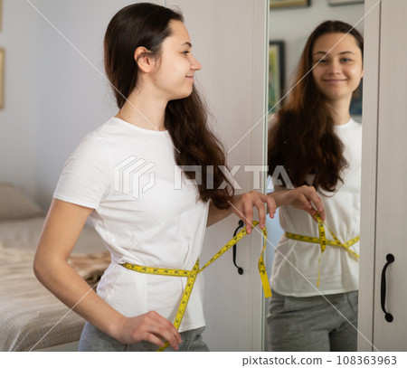 Young pretty girl with measuring tape at bedroom Young pretty girl with measuring tape at bedroom 108363963