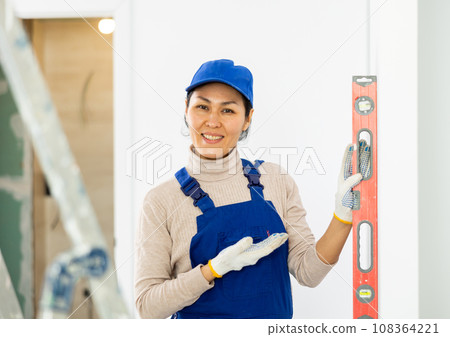 Woman worker measuring wall with spirit level 108364221