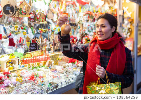 Woman with a Christmas tree toy in her hand buys decorations for new year Woman with a Christmas tree toy in her hand buys decorations for new year 108364259