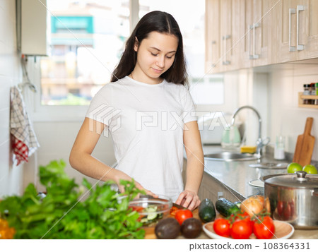 Young woman chopping vegetables at home kitchen 108364331
