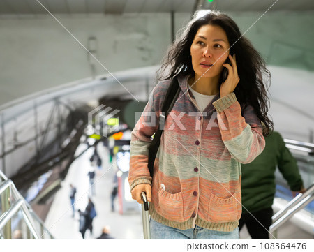 Woman with backpack and suitcase walking in subway escolator 108364476