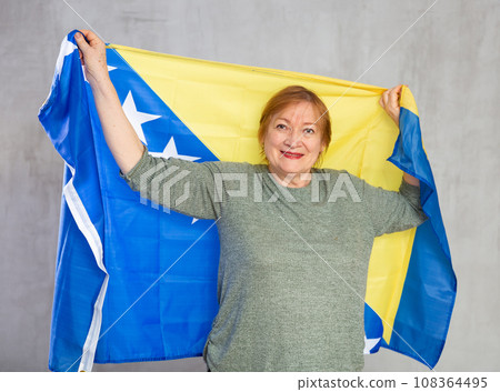 Cheerful senior woman standing confidently with bosnian flag 108364495