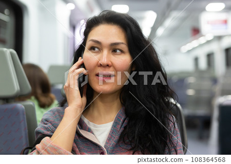 Woman traveler talking on mobile phone in subway train car 108364568