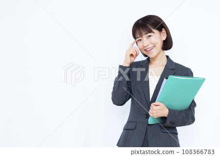 A working woman in her 30s wearing a suit smiling and thinking 108366783