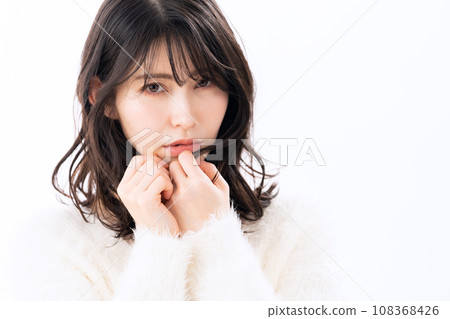 A middle-aged woman wearing a knitwear doing skin care against a white background 108368426