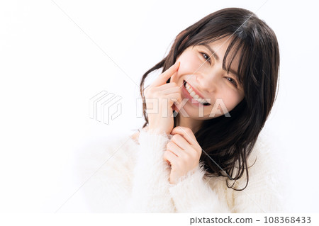A middle-aged woman wearing a knitwear doing skin care against a white background 108368433
