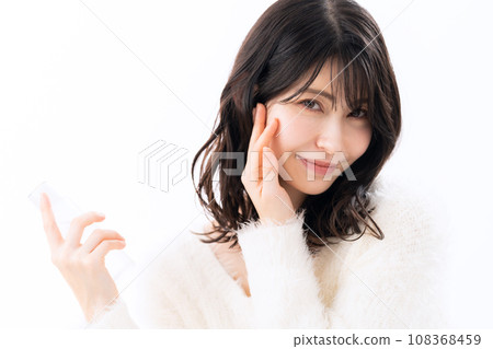 一位穿著針織品的中年婦女在白色背景下做皮膚護理 一位穿著針織品的中年婦女在白色背景下做皮膚護理 108368459