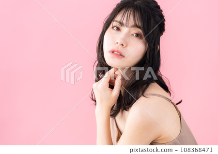 A middle-aged woman doing skin care with a pink background A middle-aged woman doing skin care with a pink background 108368471