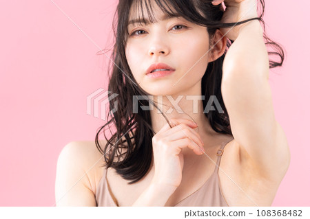 A middle-aged woman doing skin care with a pink background 108368482