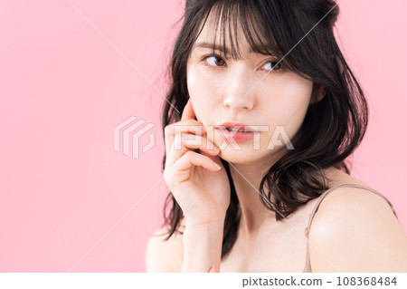 A middle-aged woman doing skin care with a pink background A middle-aged woman doing skin care with a pink background 108368484