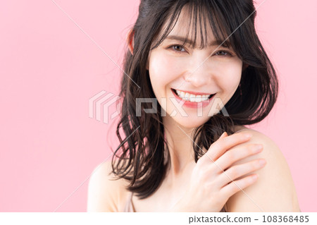 A middle-aged woman doing skin care with a pink background 108368485