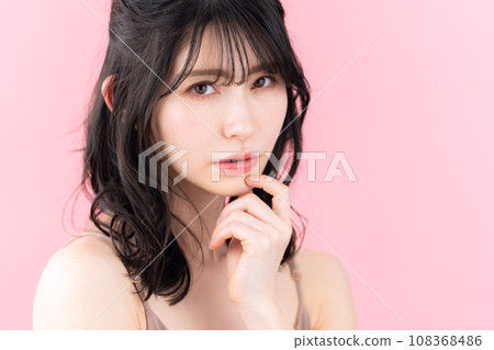 A middle-aged woman doing skin care with a pink background A middle-aged woman doing skin care with a pink background 108368486