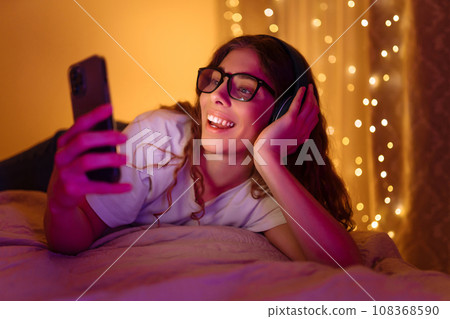 Woman in headphones before bedtime listening online to relaxing music. Remote work, internet concept 108368590