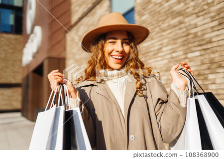 Woman with shopping bags near mall. Consumerism, purchases, shopping, lifestyle, sale concept. 108368900