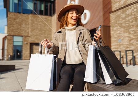 Woman with shopping bags near mall. Consumerism, purchases, shopping, lifestyle, sale concept. 108368905