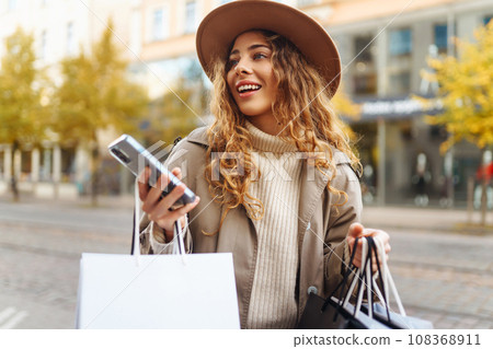 Woman with shopping bags near mall. Consumerism, purchases, shopping, lifestyle, sale concept. Woman with shopping bags near mall. Consumerism, purchases, shopping, lifestyle, sale concept. 108368911