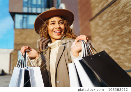 Woman with shopping bags near mall. Consumerism, purchases, shopping, lifestyle, sale concept. 108368912