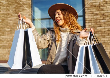 Woman with shopping bags near mall. Consumerism, purchases, shopping, lifestyle, sale concept. 108368921