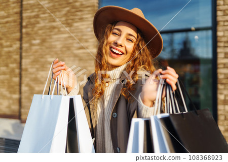 Woman with shopping bags near mall. Consumerism, purchases, shopping, lifestyle, sale concept. Woman with shopping bags near mall. Consumerism, purchases, shopping, lifestyle, sale concept. 108368923