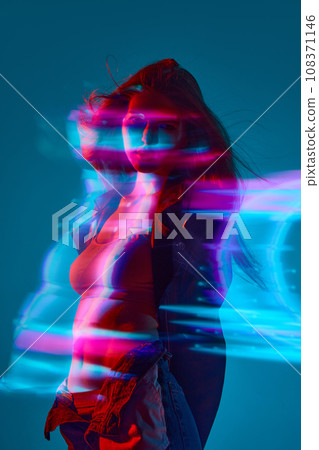 Silhouette of young woman standing against blue background with mixed neon lights effect. Hologram 108371146