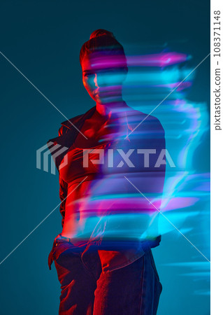 Silhouette of young woman standing against blue background with mixed neon lights effect. Hologram 108371148