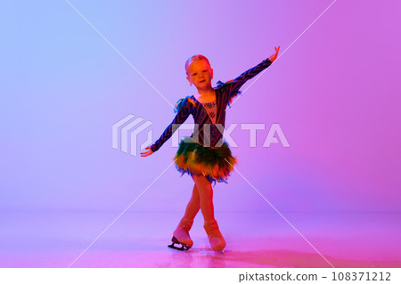 Beautiful child, little cute girl performing figure skating in cute dress, dancing against gradient pink purple background in neon light 108371212