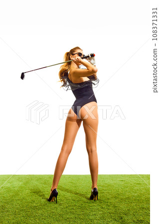 Sexy young woman with slim, beautiful body in elegant bodysuit posing on heels with golf club isolated over white background. Back view Sexy young woman with slim, beautiful body in elegant bodysuit posing on heels with golf club isolated over white background. Back view 108371331