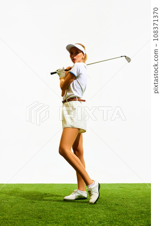 Full-length image of beautiful, blonde, young girl playing golf, standing with club on grass field isolated over white background Full-length image of beautiful, blonde, young girl playing golf, standing with club on grass field isolated over white background 108371370