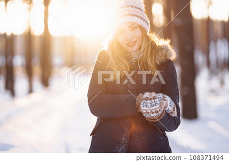 Happy young woman plays with a snow in sunny winter day. Girl enjoys winter, frosty day. Happy young woman plays with a snow in sunny winter day. Girl enjoys winter, frosty day. 108371494