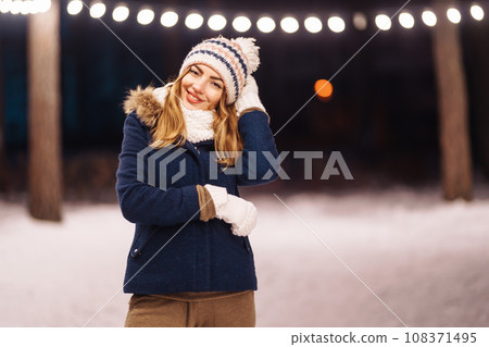 Cheerful young woman holding sparkler in hand in winter forest. Happy cute girl posing with sparkler Cheerful young woman holding sparkler in hand in winter forest. Happy cute girl posing with sparkler 108371495