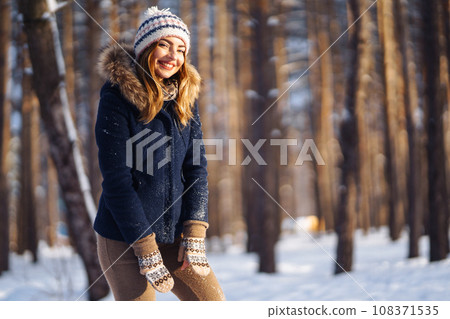 Happy young woman plays with a snow in sunny winter day. Girl enjoys winter, frosty day. 108371535