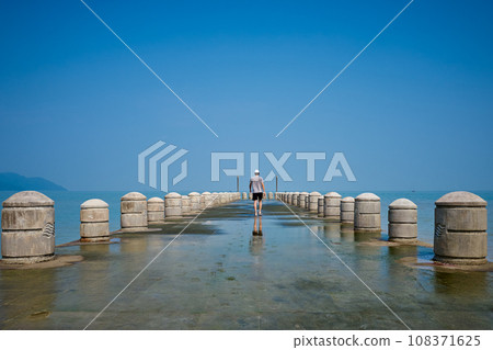 Tourists leisurely walk on the pier at the Batu Ferringhi beach Tourists leisurely walk on the pier at the Batu Ferringhi beach 108371625
